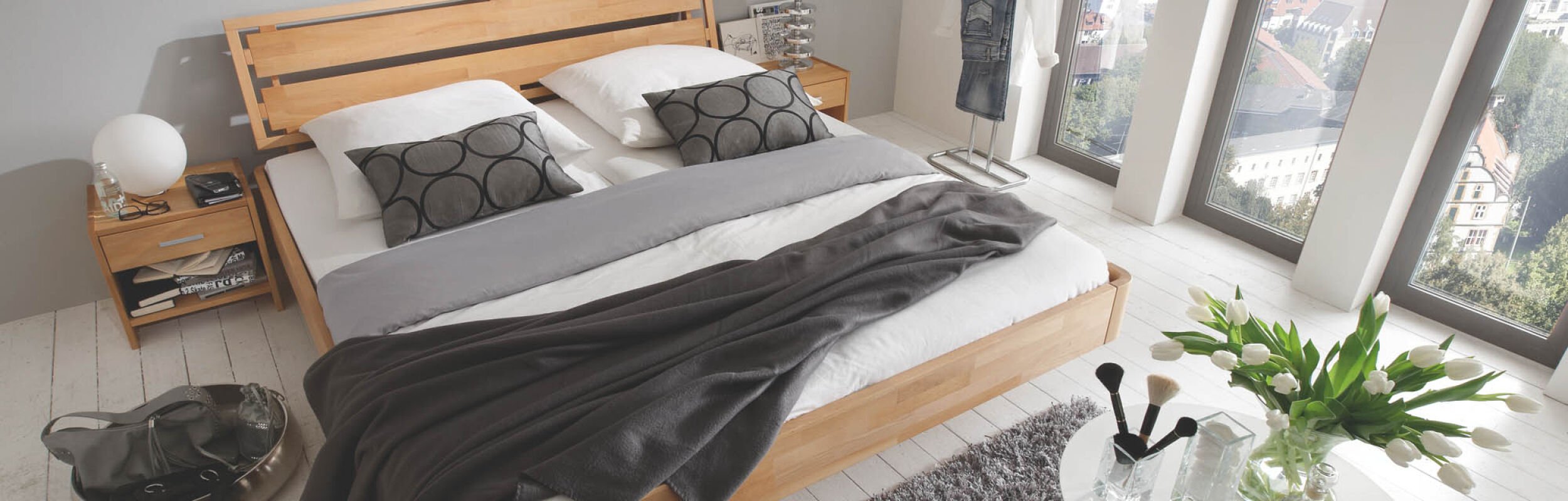 Ausstellungsstück Bett aus hellen Holz mit grauer Decke